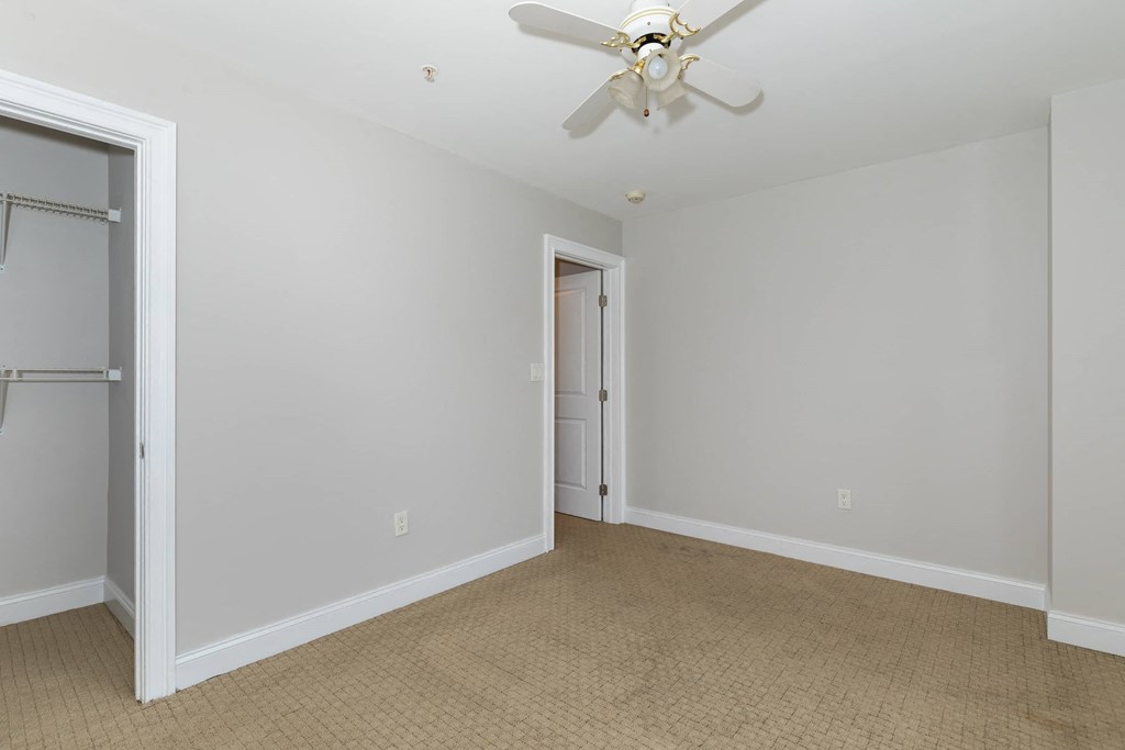 a bedroom with white walls and a ceiling fan