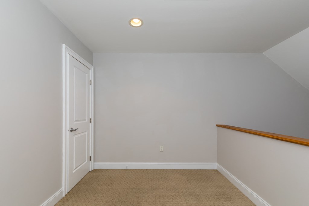 a bedroom with white walls and a white door and a carpet