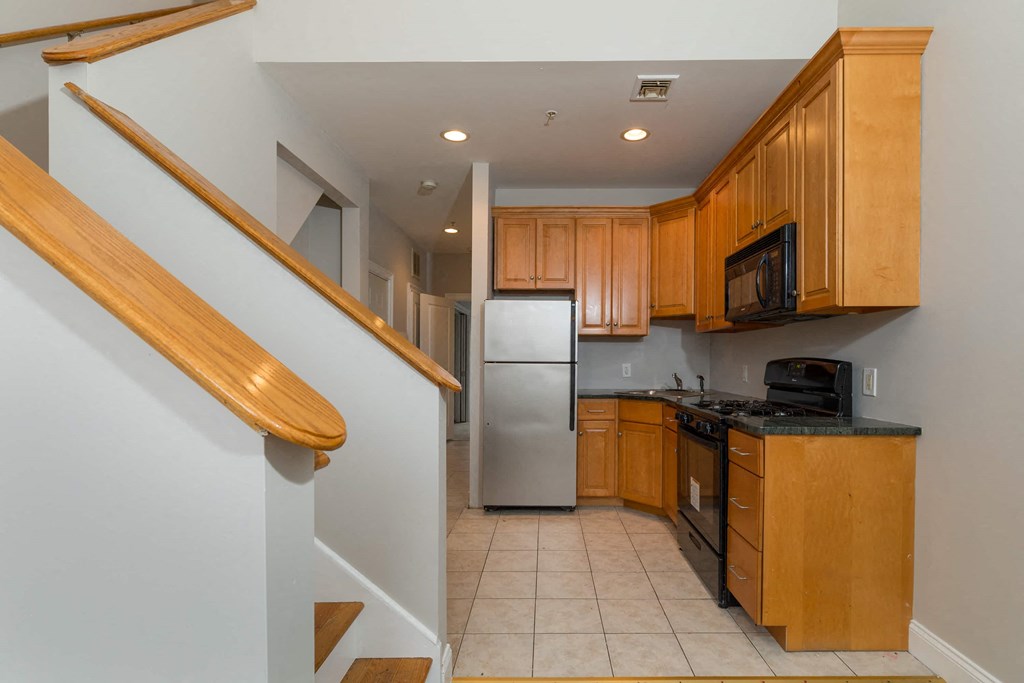 a kitchen with wooden cabinets and a staircase