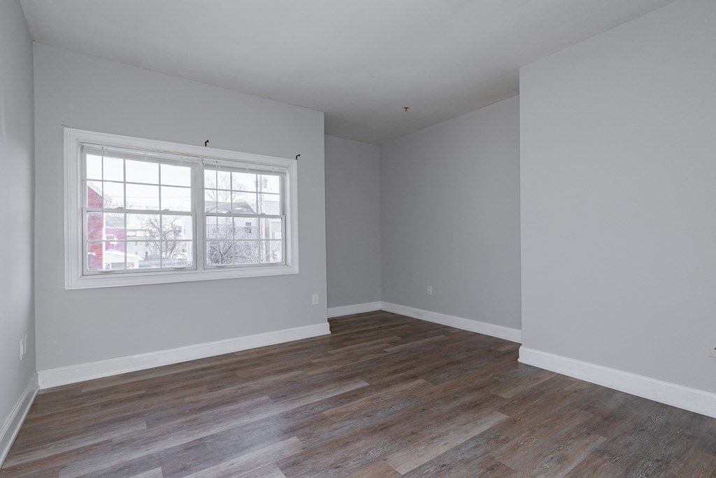 an empty living room with wood floors and a window