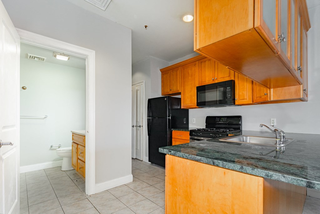 a kitchen with black appliances and wooden cabinets and a sink