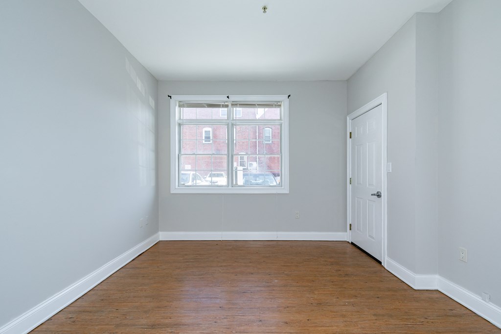 an empty room with wood floors and a window