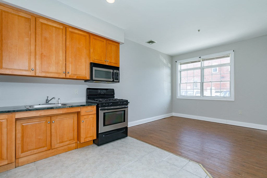 an empty kitchen with wooden cabinets and a window