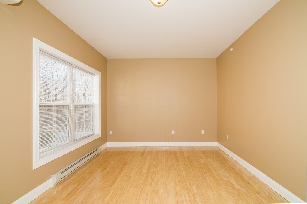 an empty living room with a large window and wooden floors
