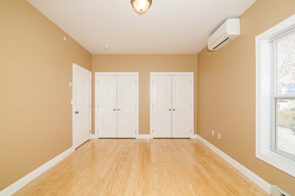 an empty living room with white doors and wood floors