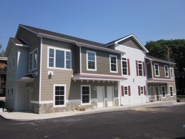 a gray house with red doors and a stone wall