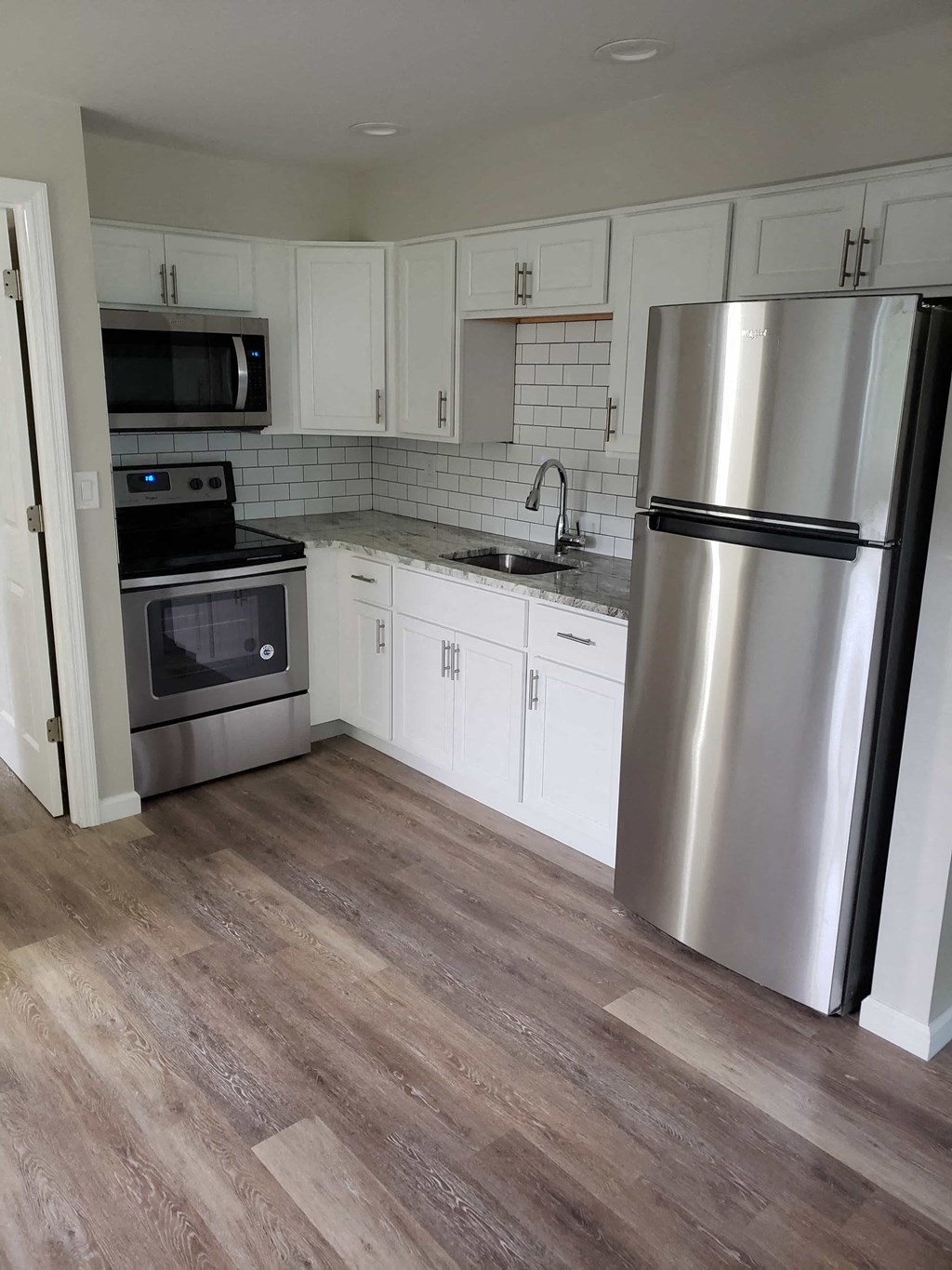 a renovated kitchen with stainless steel appliances and white cabinets