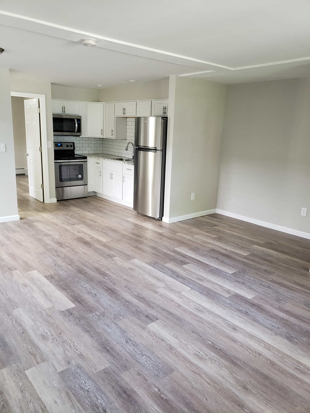 a renovated kitchen with wood floors and a stainless steel refrigerator