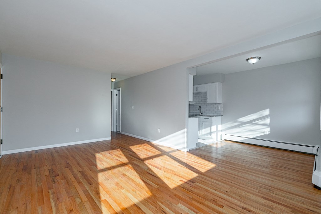 an empty living room with wood floors and a piano