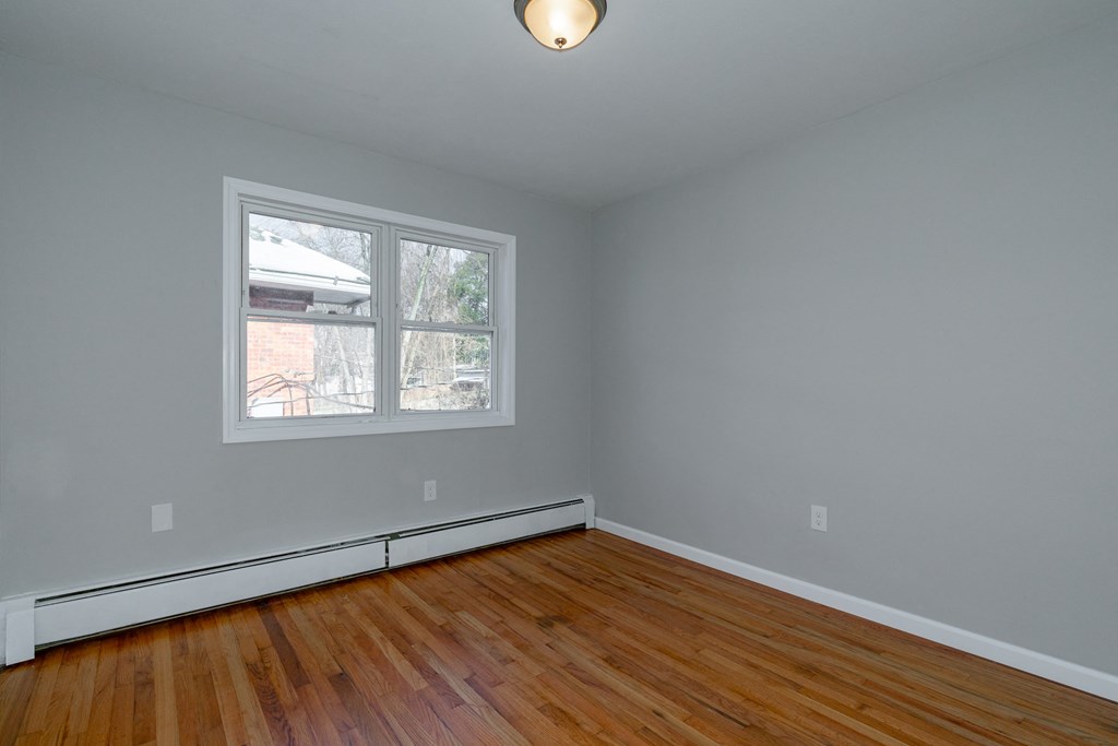 an empty room with wood floors and a window