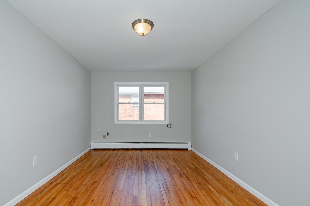 an empty room with wooden floors and a window