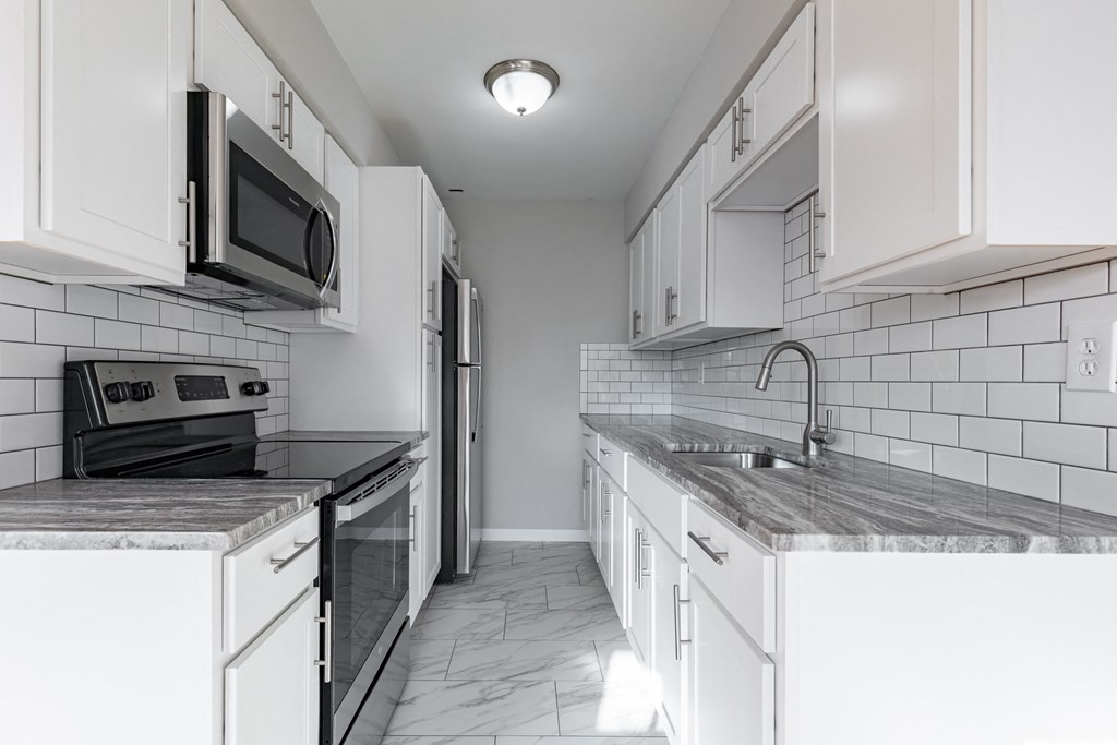 an empty kitchen with white cabinets and a black stove