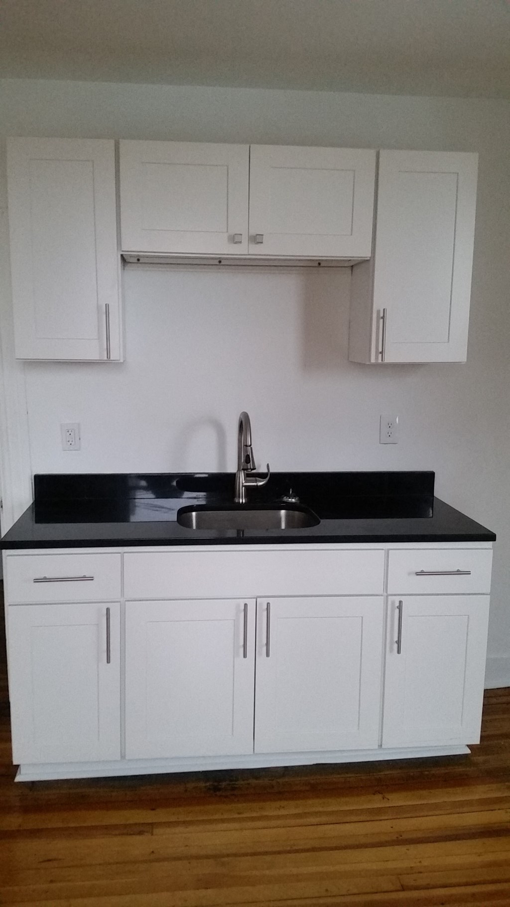 an empty kitchen with white cabinets and a sink