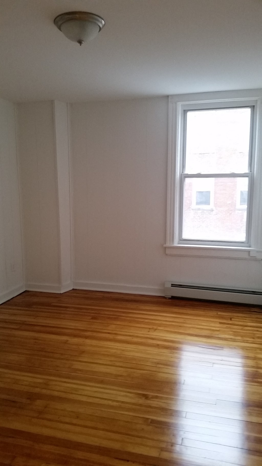an empty room with wooden floors and a window
