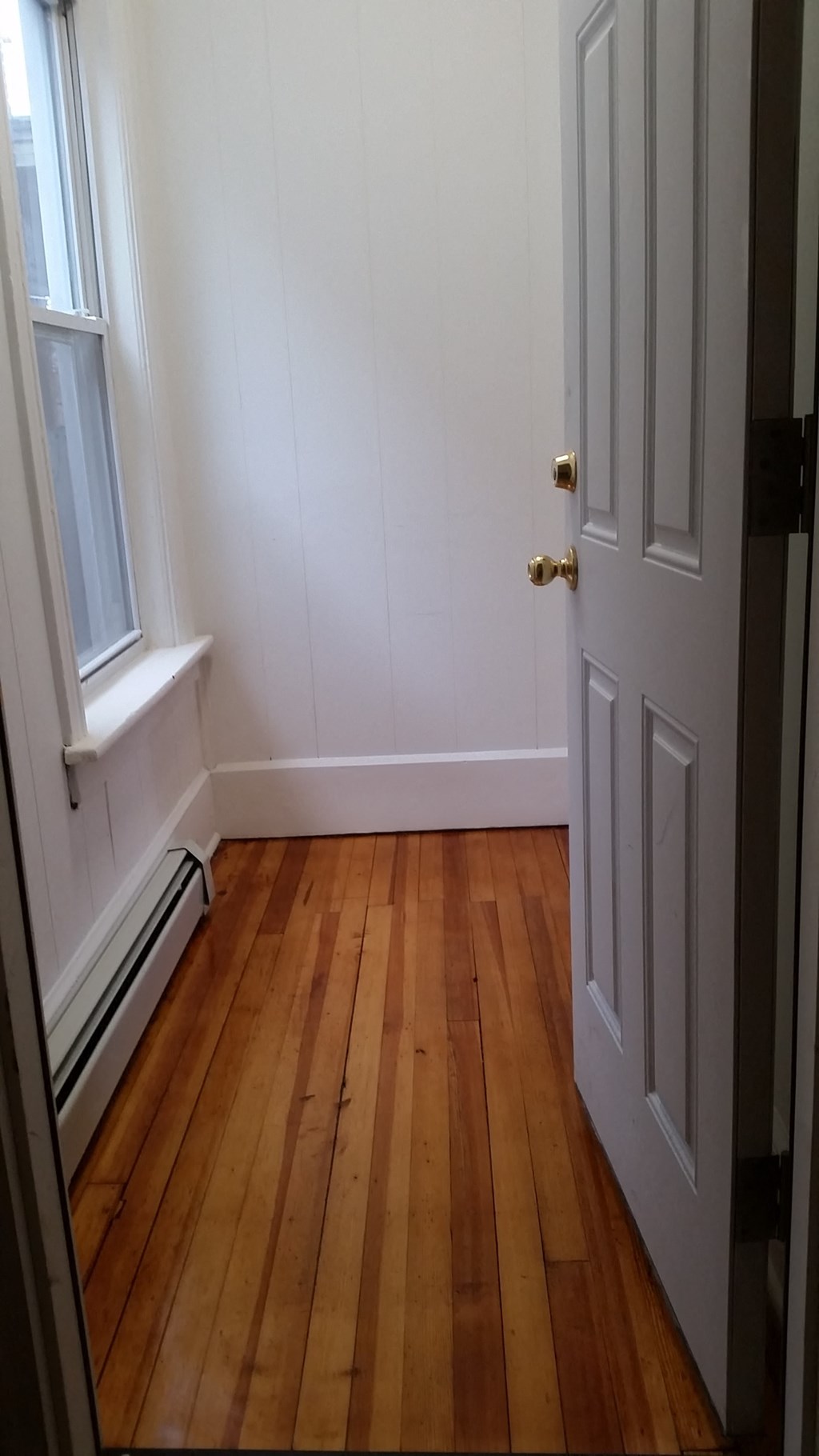 a small room with wooden floors and a white door
