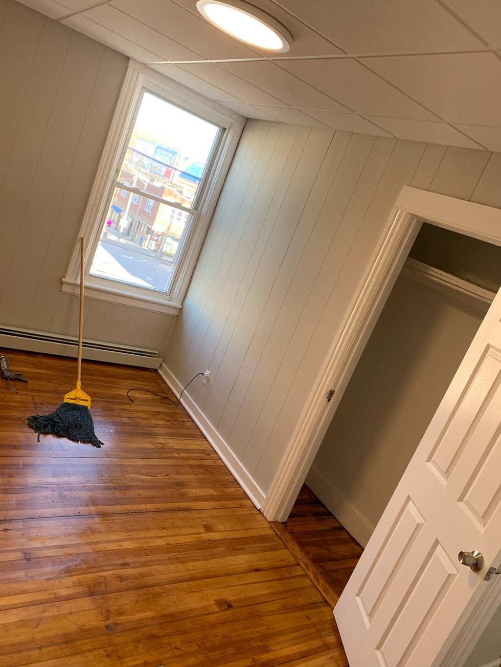 a room with a mop hanging from the ceiling and a closet and a window