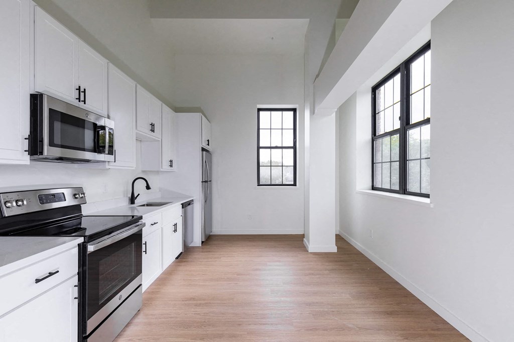 an empty kitchen with white cabinets and black appliances