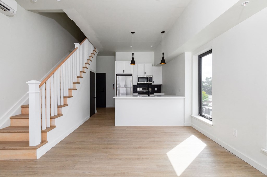 a living room with a staircase and a kitchen