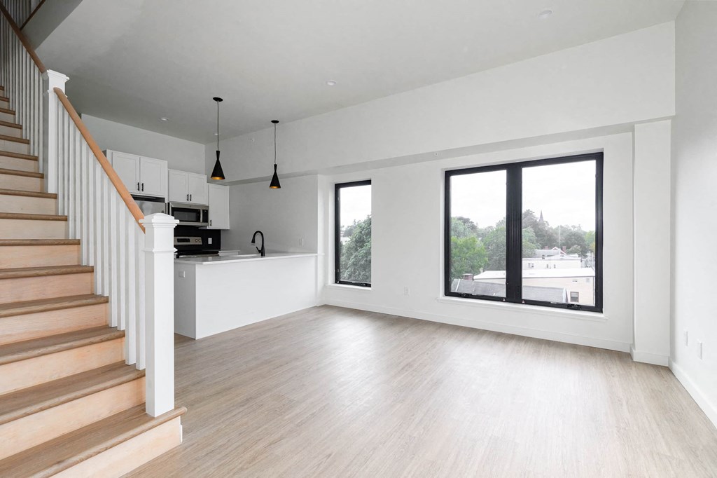 a living room with a staircase and a large window