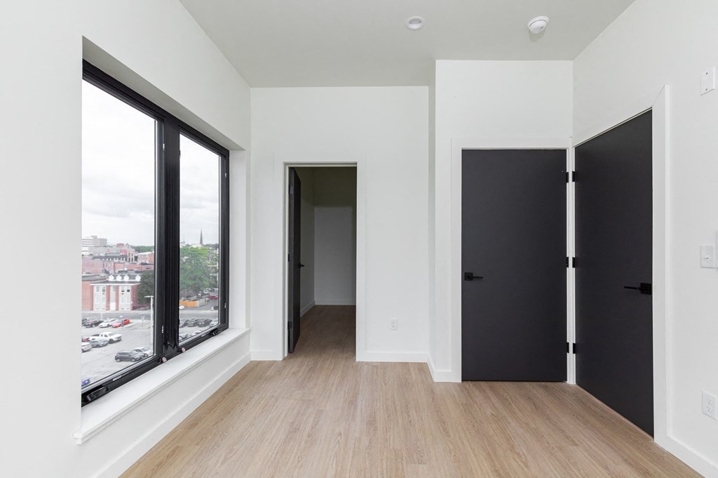 a living room with a large window and a door to a hallway
