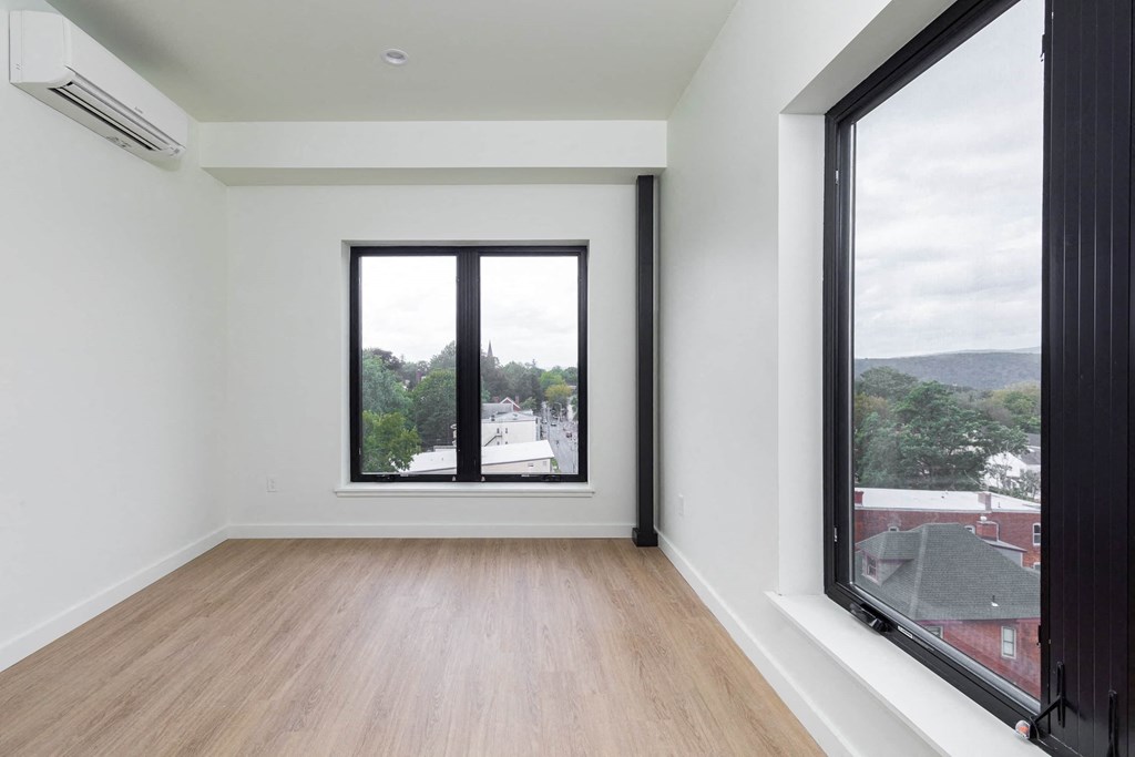 a living room with a large window and wooden floors