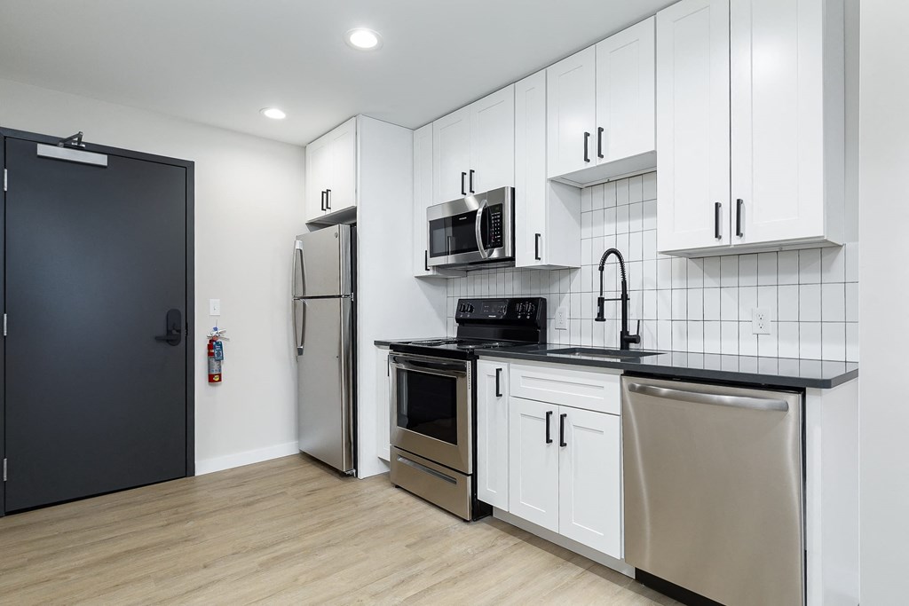 a kitchen with white cabinets and stainless steel appliances and a refrigerator