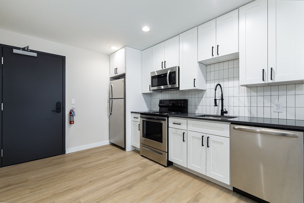 a renovated kitchen with white cabinets and stainless steel appliances