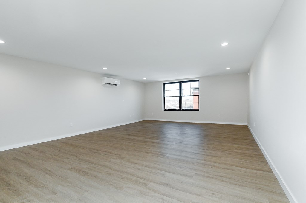 a living room with white walls and wood floors and a window