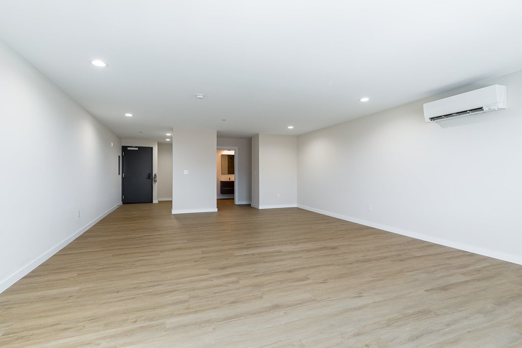 a spacious living room with white walls and wood floors