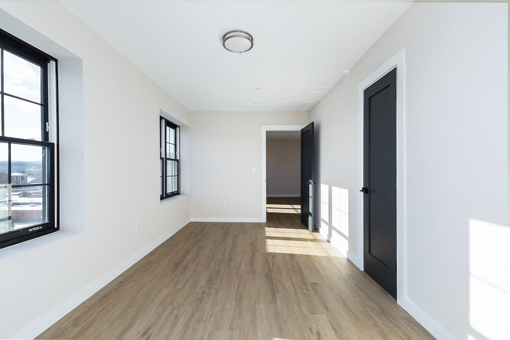 a living room with white walls and wood floors and a black door