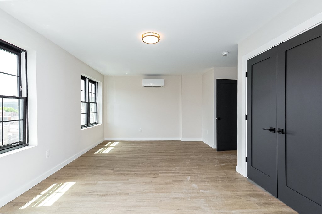 a hallway with black doors and white walls and a wooden floor