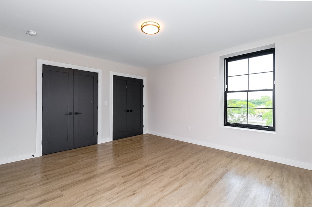 an empty living room with black doors and a window