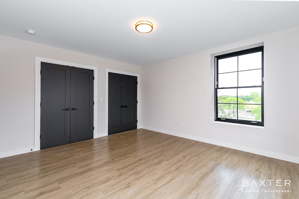 a living room with white walls and wood floors and black doors