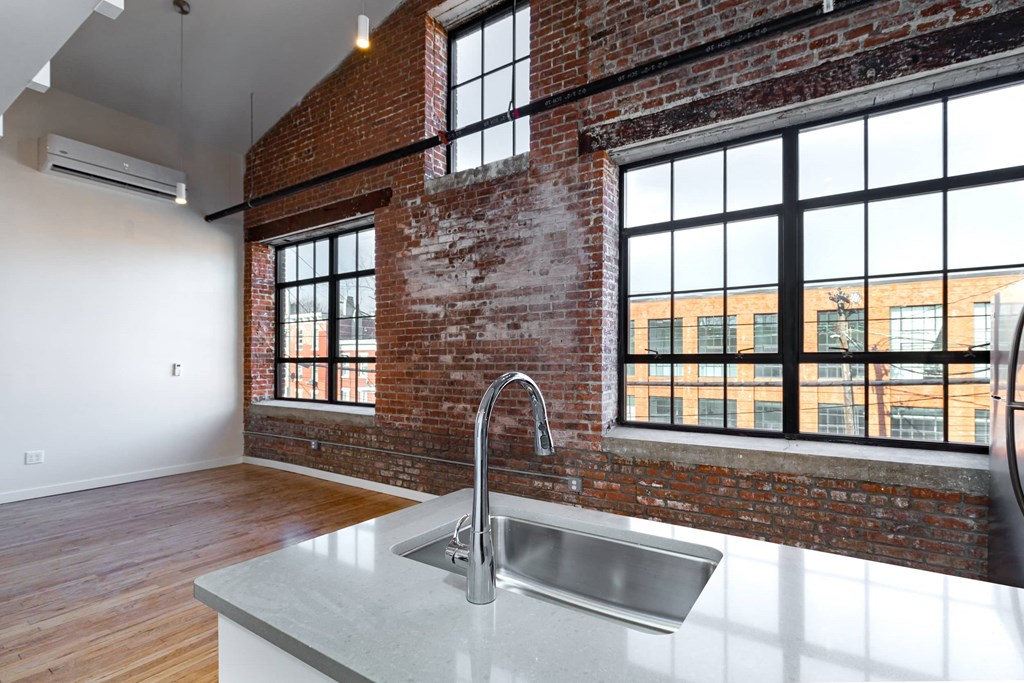 an open kitchen with a sink and a exposed brick wall