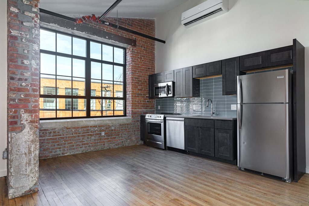 an open kitchen with a large window and a stainless steel refrigerator