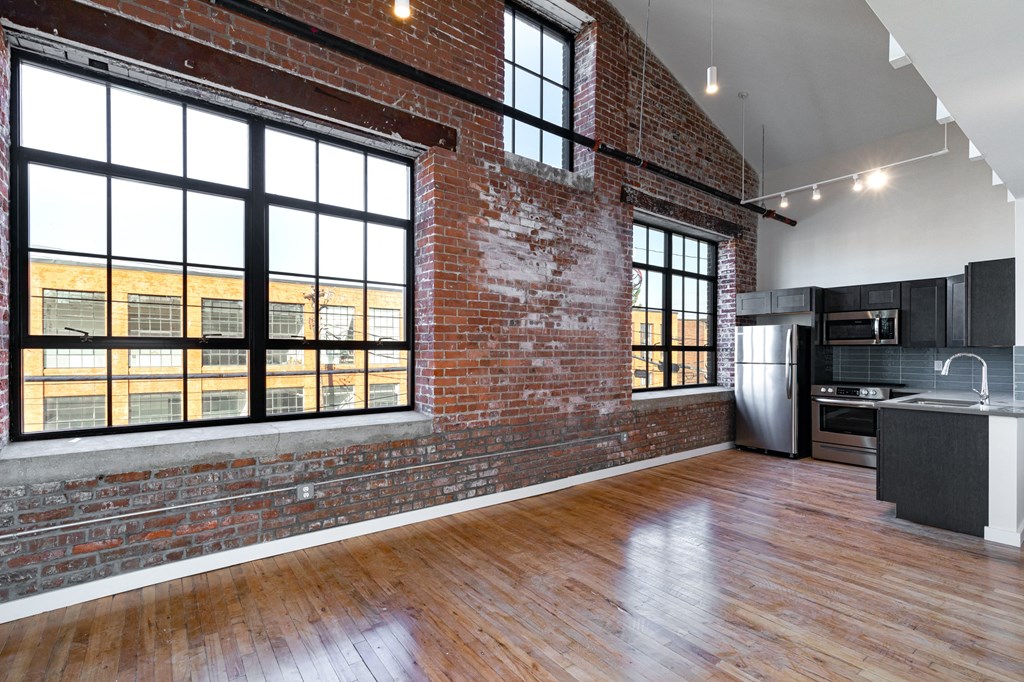 an empty living room with a large window and a kitchen