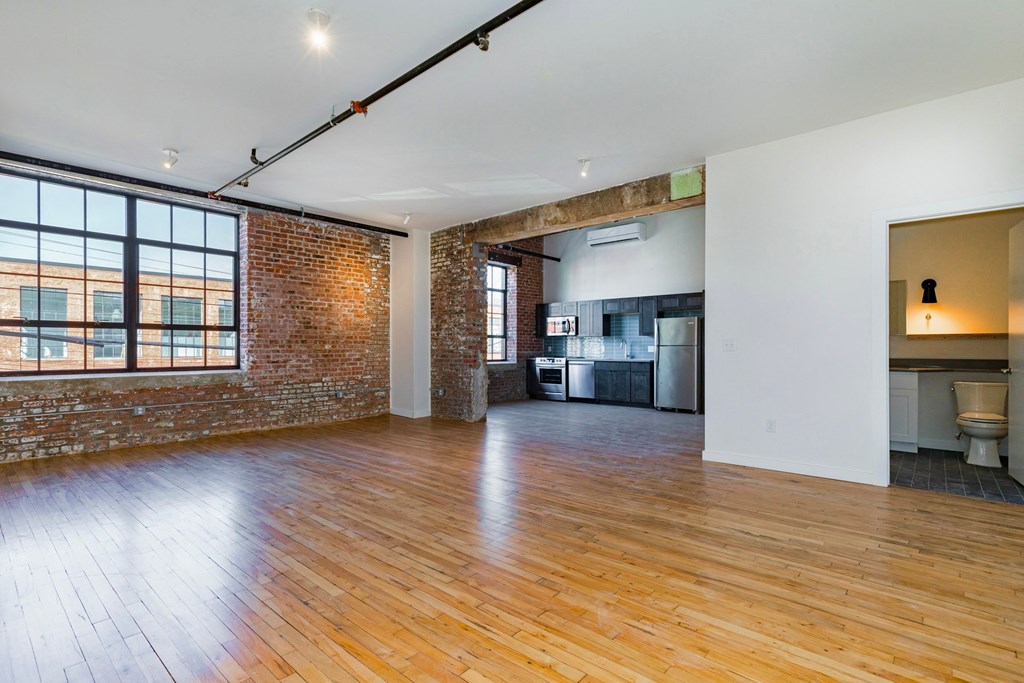 an open living room with exposed brick and wood floors and a large window