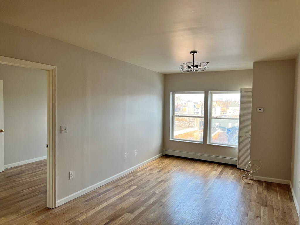 an empty living room with wood floors and a window