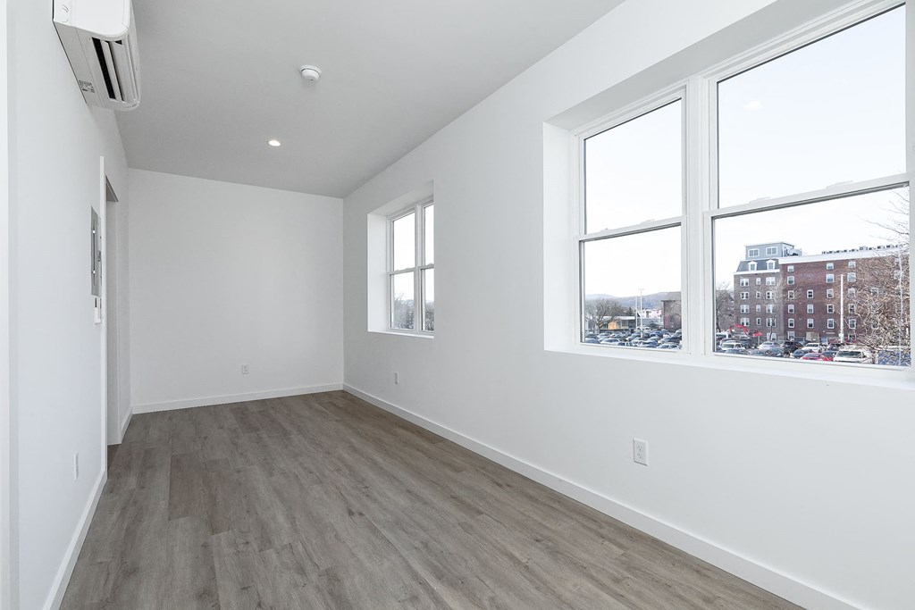 a living room with white walls and three windows