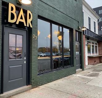 the exterior of a bar with a black door and windows