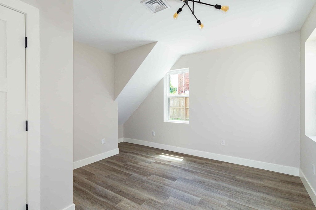 an empty room with white walls and a window and wooden floors