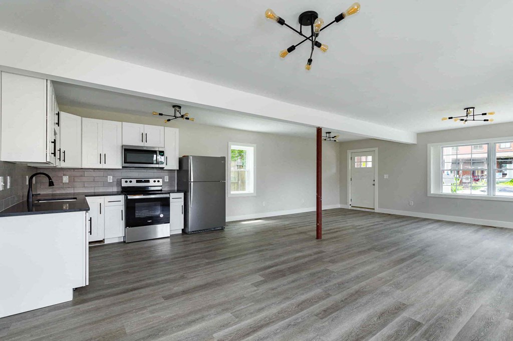 a kitchen and living room with white cabinets and stainless steel appliances