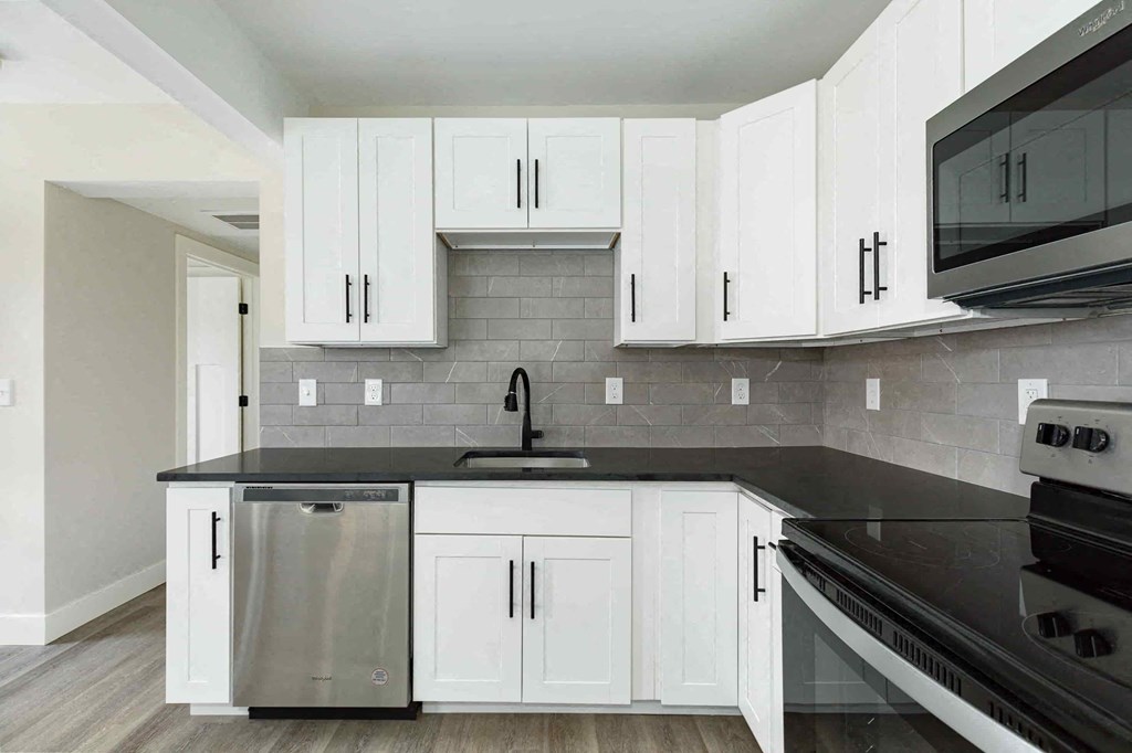 a kitchen with white cabinets and a black counter top