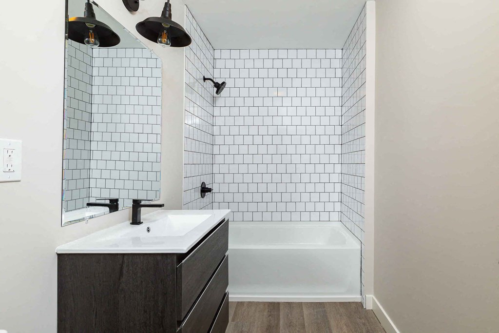 a white tiled bathroom with a sink and a bath tub