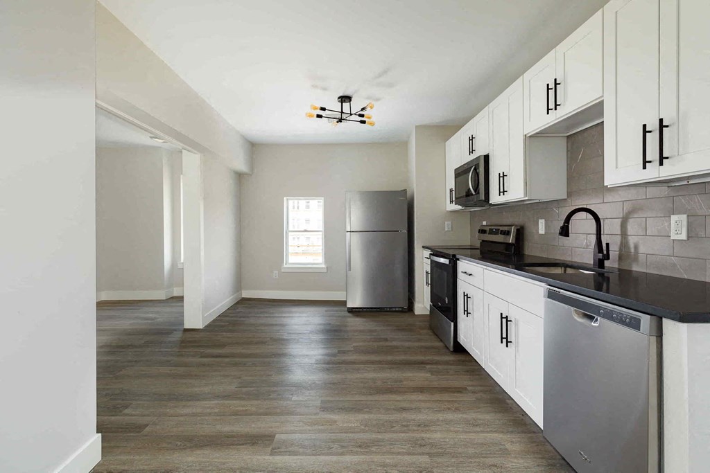 an empty kitchen with white cabinets and a stainless steel refrigerator