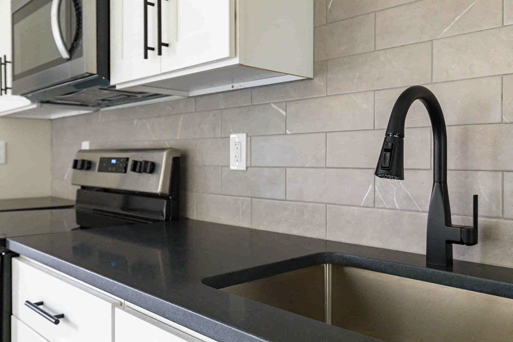 a kitchen with a sink and a black counter top