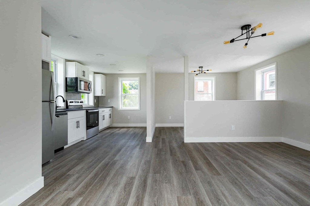 an empty kitchen and living room with wood floors