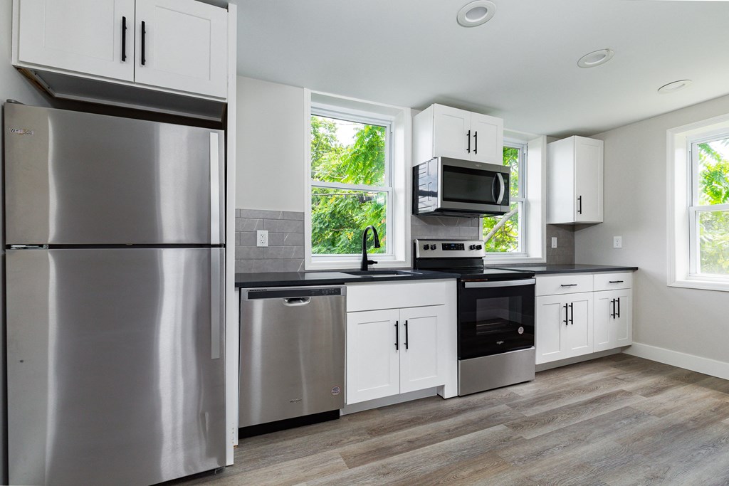 an empty kitchen with stainless steel appliances and white cabinets