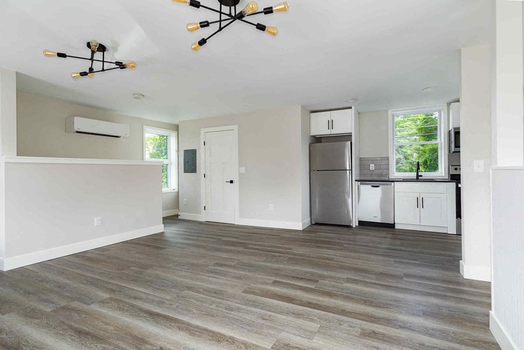 an empty kitchen and living room with a refrigerator and a sink