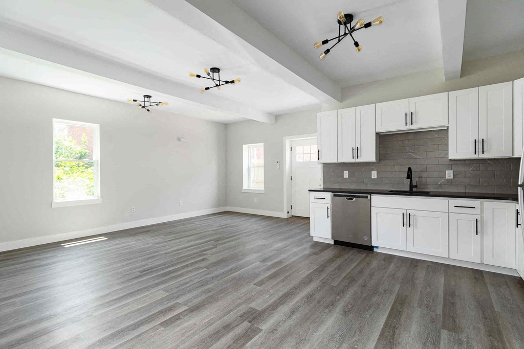 an empty kitchen and living room with white cabinets